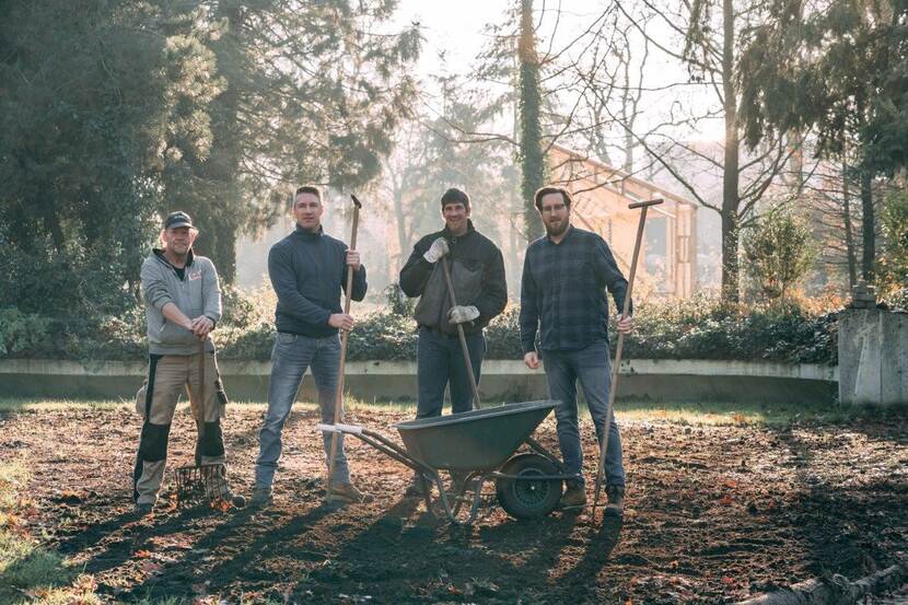 Vier mannen met tuingereedschap en een kruiwagen